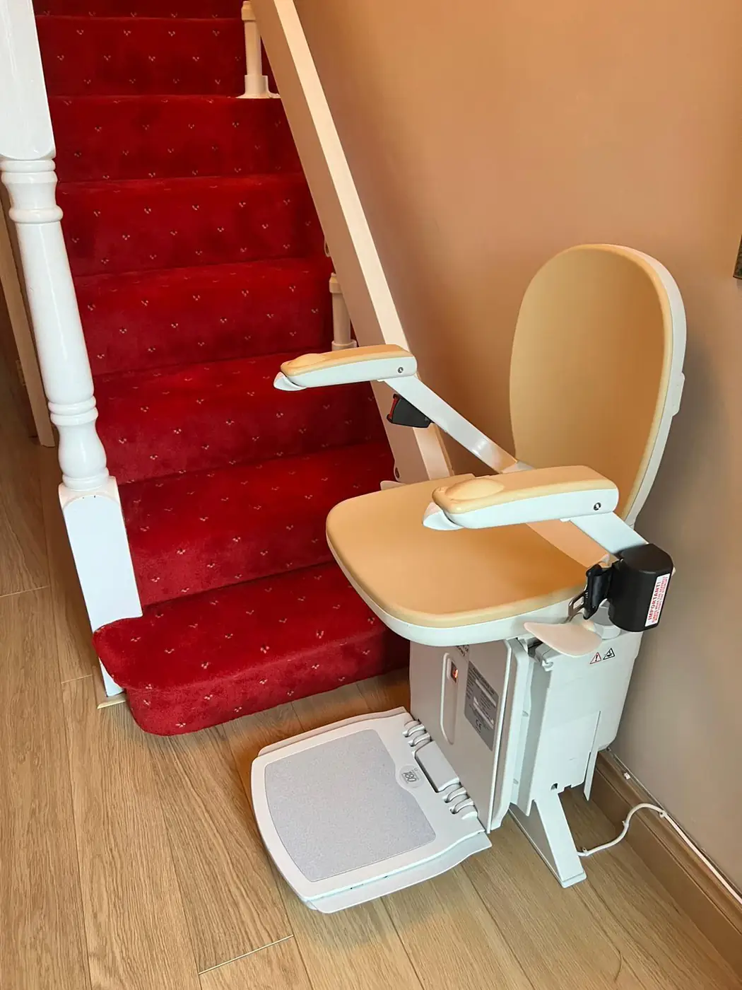 Straight stairlift parked at the foot of a carpeted staircase