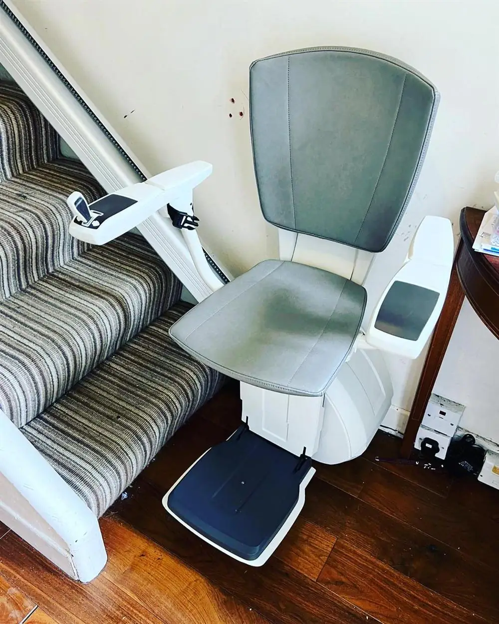 Grey-seat straight stairlift installed beside striped carpeted stairs in Cork