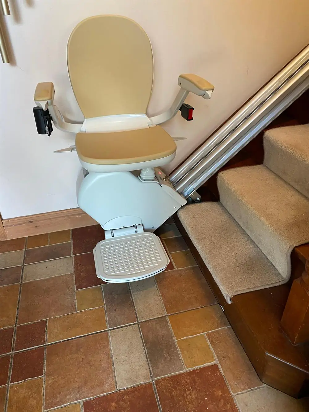 Beige straight stairlift installed at a tiled lower landing in Tipperary