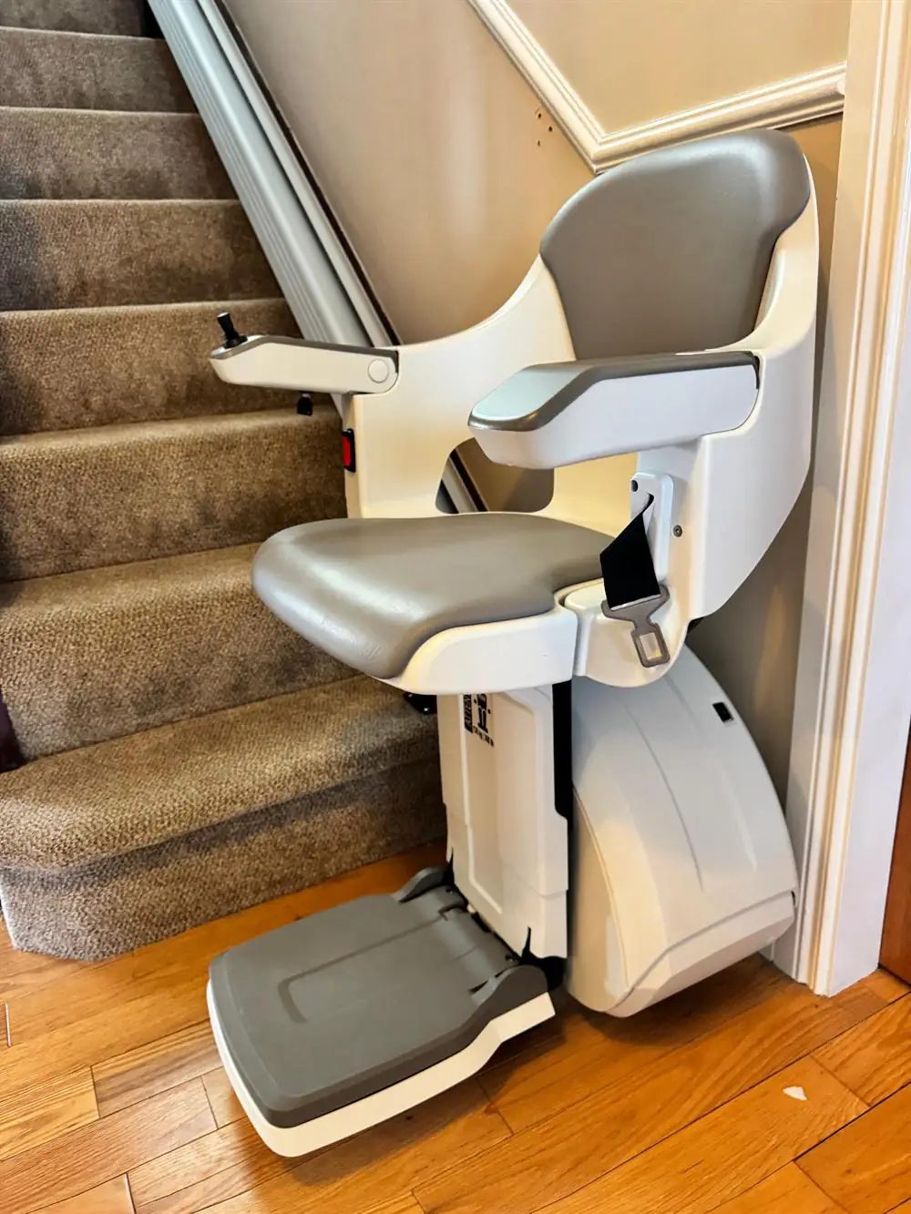 Grey-seat straight stairlift installed at the foot of a carpeted staircase in Westmeath
