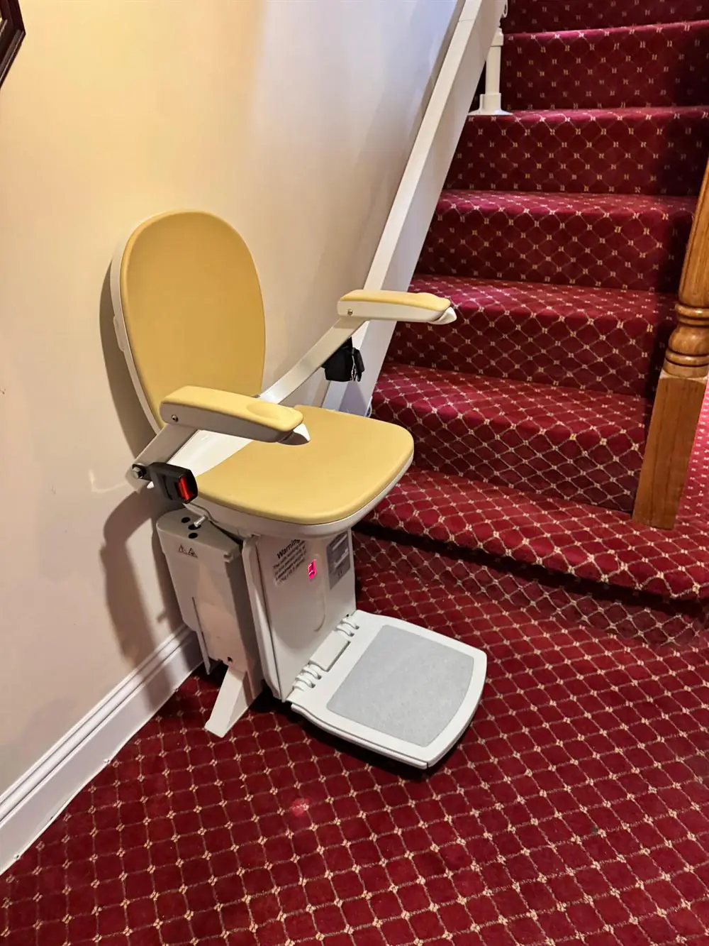 Beige straight stairlift installed beside a red-carpeted staircase in Kilkenny