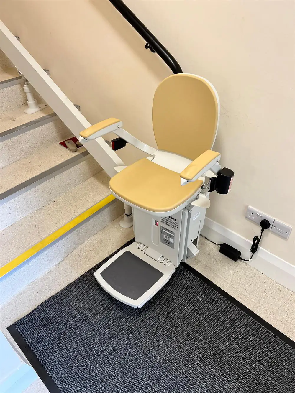Beige curved stairlift installed beside a broad staircase in Roscommon