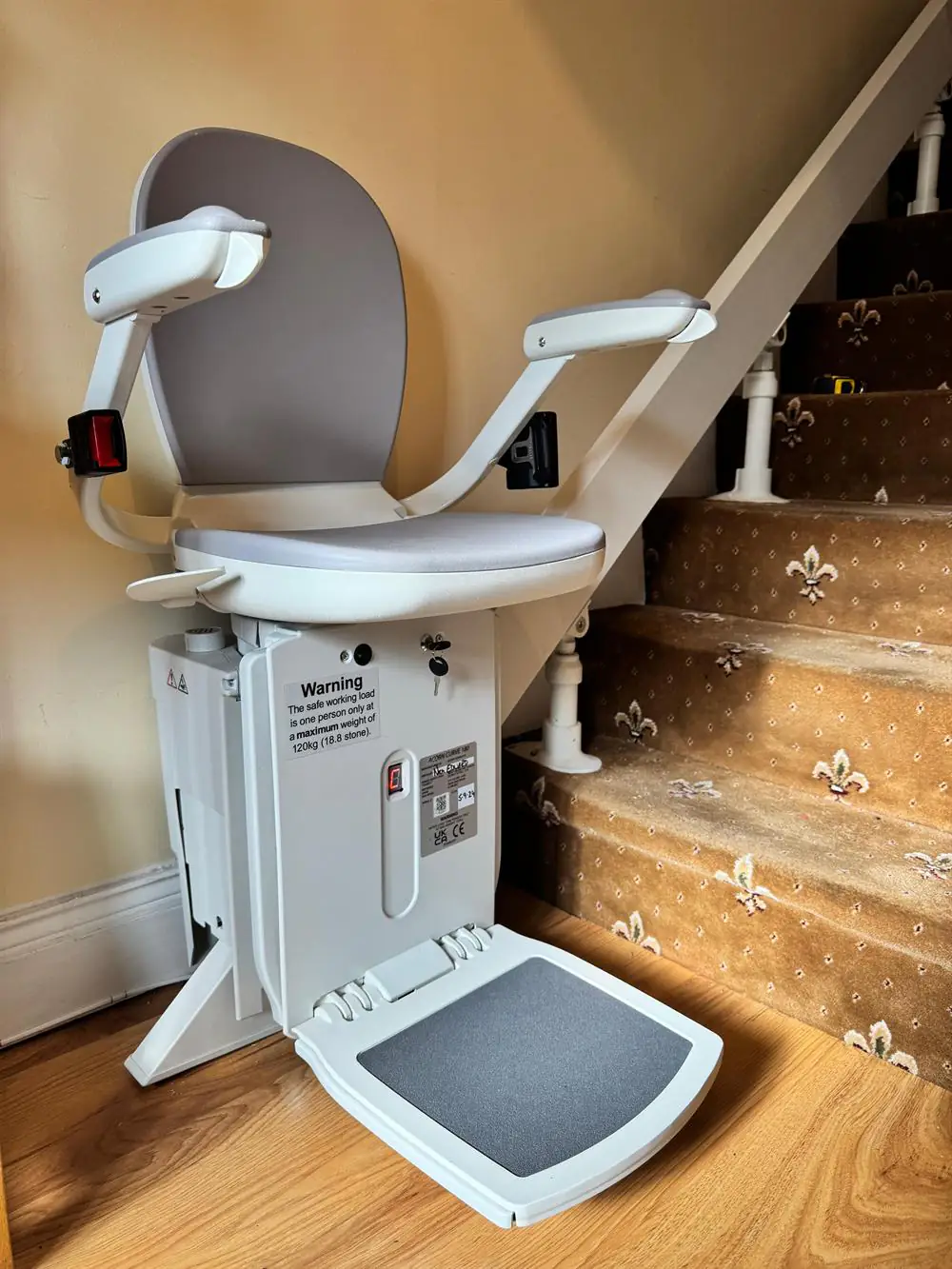 Grey reconditioned stairlift fitted beside patterned carpeted stairs in Kerry