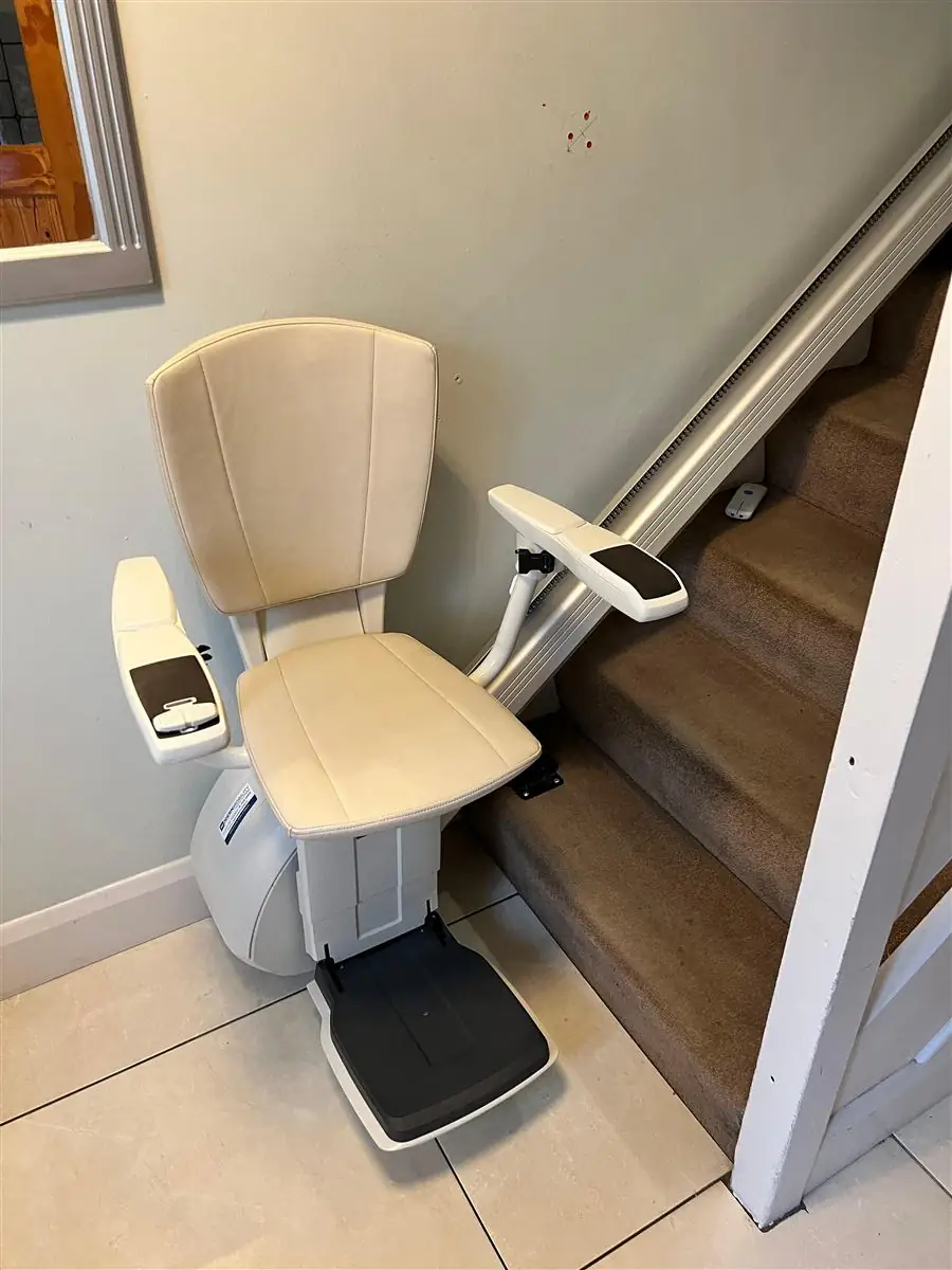 Straight stairlift parked at the bottom of a timber staircase