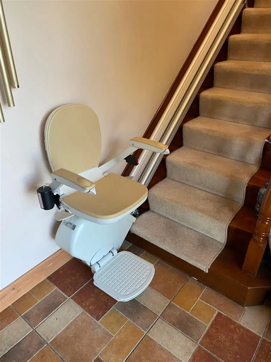 Straight stairlift fitted neatly beside a carpeted staircase