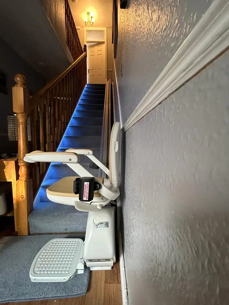 Straight stairlift fitted beside a long blue-carpeted staircase
