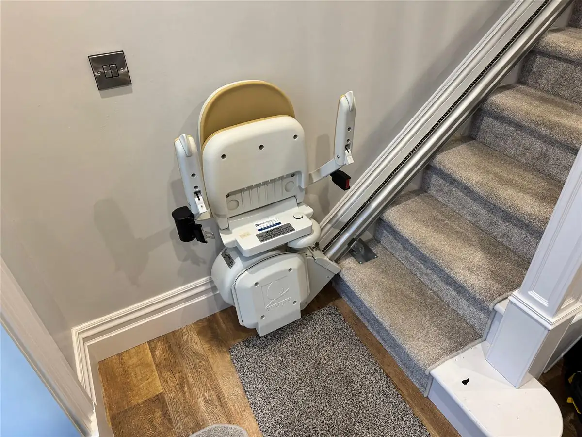Straight stairlift rail fitted cleanly along a carpeted staircase