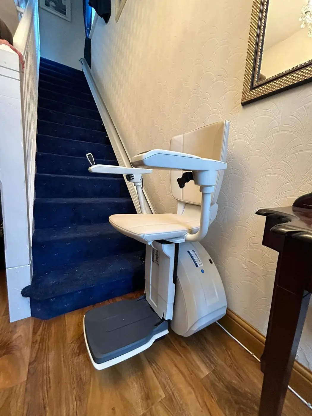 Clean rental stairlift set up beside a blue-carpeted staircase