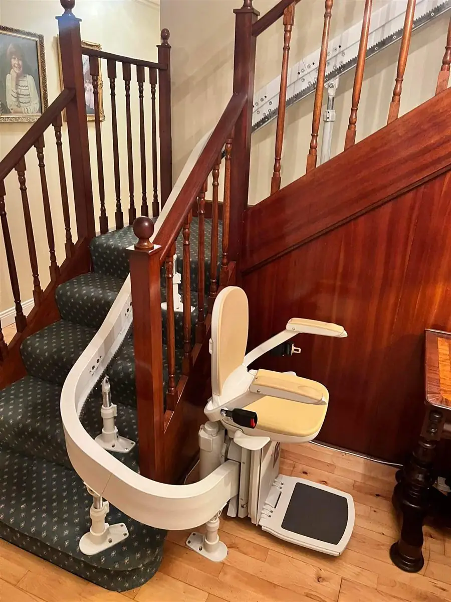 Curved stairlift rail wrapped neatly around a timber newel post