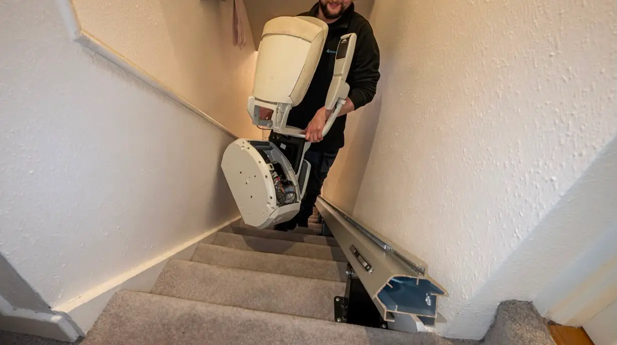 Engineer carrying a stairlift carriage while transferring it to another home